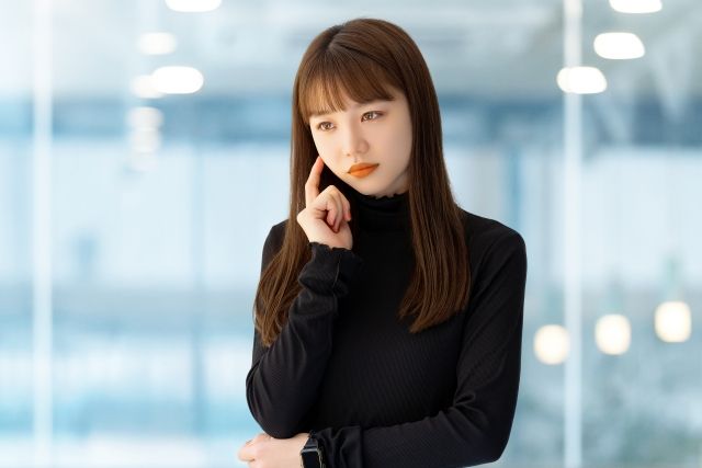頬に手を当てて悩む女性